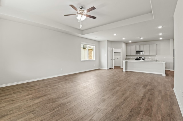 unfurnished living room featuring recessed lighting, ceiling fan, baseboards, and wood finished floors