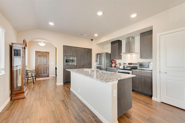754 Brookline Dr, Lavon, TX 75166 - kitchen with wall chimney range hood, appliances with stainless steel finishes, arched walkways, a sink, and light wood-type flooring