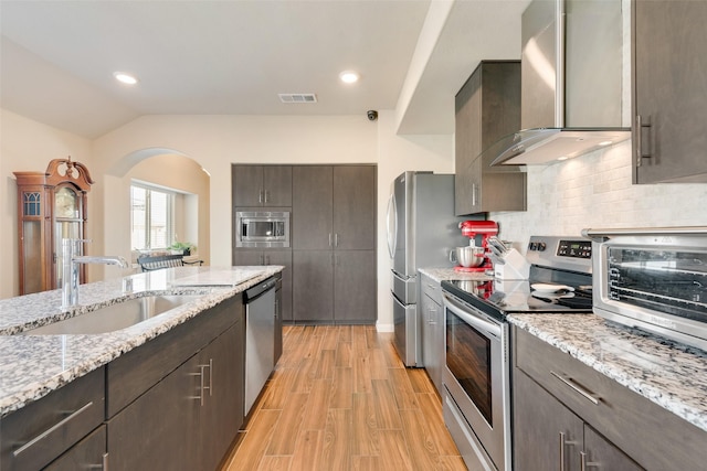 754 Brookline Dr, Lavon, TX 75166 - kitchen with stainless steel appliances, wall chimney range hood, arched walkways, tasteful backsplash, and vaulted ceiling