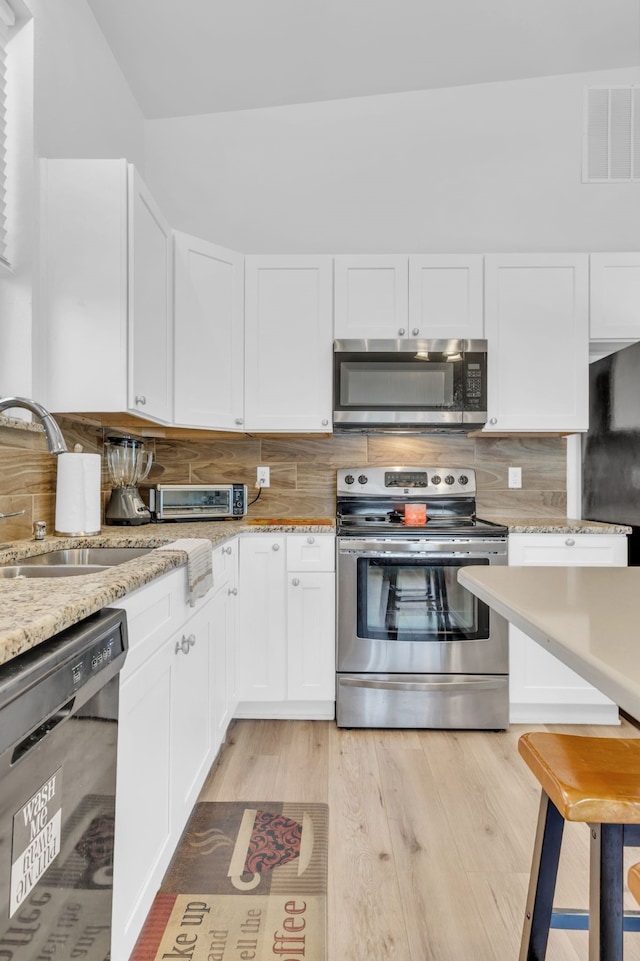 kitchen featuring a sink, visible vents, appliances with stainless steel finishes, and white cabinetry