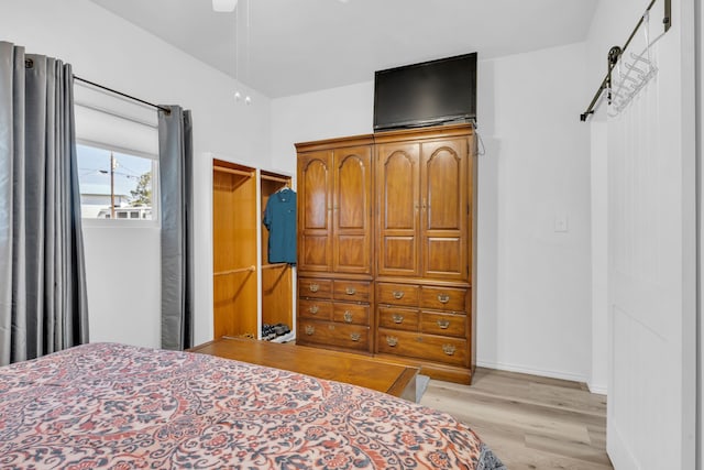 bedroom with light wood-style flooring, a ceiling fan, and baseboards