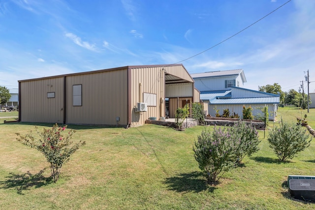 rear view of house featuring cooling unit, an outbuilding, and a lawn