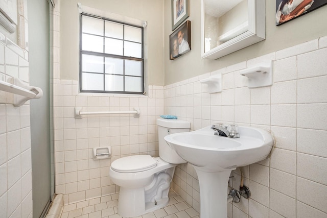 1128 Mason Dr, Hurst, TX 76053 - bathroom featuring toilet, tile patterned floors, tile walls, and a wainscoted wall