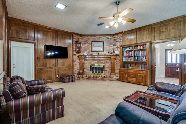 9A Rhea Mills Cir, Prosper, TX 75078 - living area with light carpet, a ceiling fan, a brick fireplace, a textured ceiling, and wood walls