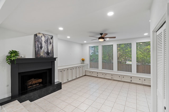 unfurnished living room with a fireplace with raised hearth, recessed lighting, a ceiling fan, and light tile patterned floors