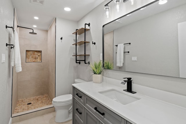 bathroom featuring visible vents, toilet, recessed lighting, vanity, and tiled shower