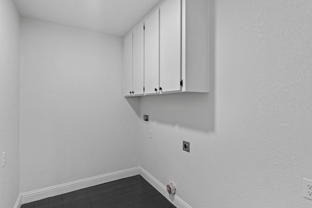 laundry area featuring hookup for a washing machine, dark tile patterned floors, electric dryer hookup, cabinet space, and baseboards