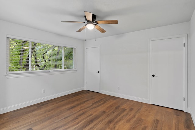 empty room with wood finished floors, ceiling fan, and baseboards