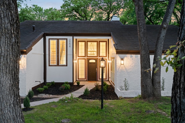 view of front of home with a chimney and brick siding