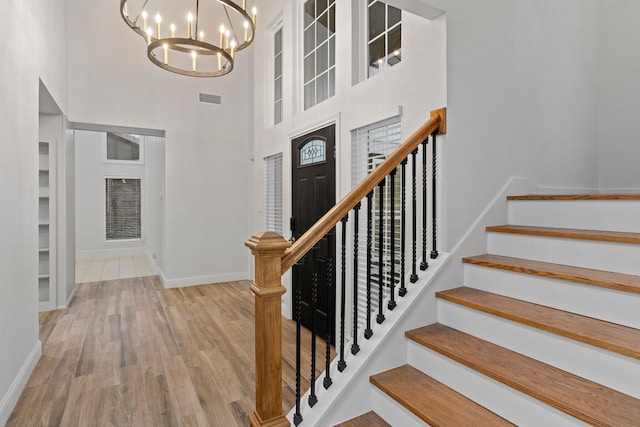 foyer featuring a chandelier, a high ceiling, visible vents, and baseboards