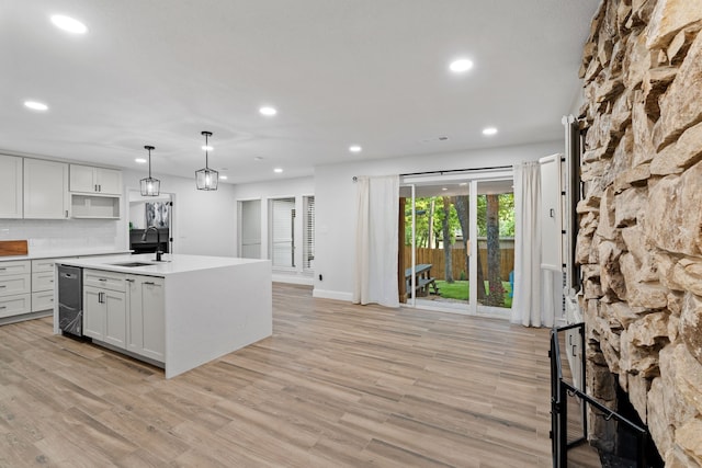 kitchen featuring a sink, light wood-style floors, light countertops, recessed lighting, and hanging light fixtures