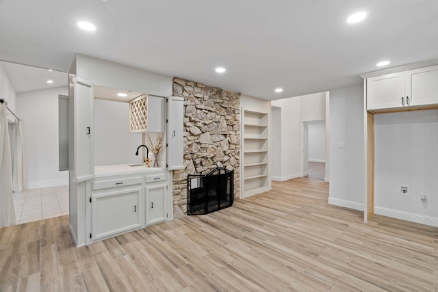 unfurnished living room featuring baseboards, recessed lighting, light wood-style flooring, and a sink