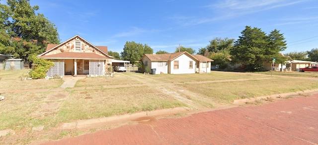 view of front of house featuring a detached carport, covered porch, driveway, and a front lawn
