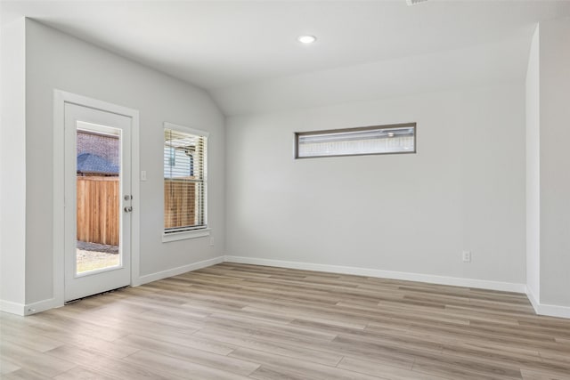 spare room featuring light wood finished floors, baseboards, vaulted ceiling, and recessed lighting