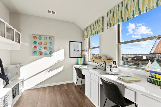 office area with visible vents, baseboards, built in desk, dark wood-type flooring, and lofted ceiling