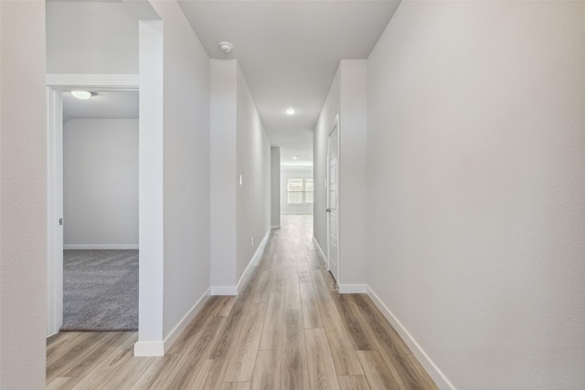 hall featuring light wood finished floors, baseboards, and recessed lighting