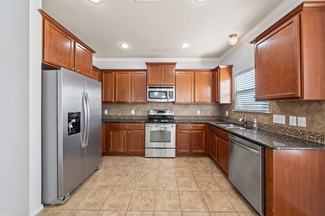 kitchen with dark stone counters, brown cabinetry, a sink, stainless steel appliances, and decorative backsplash