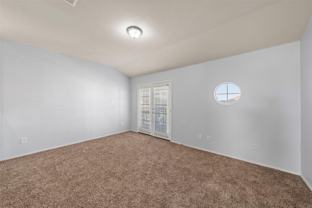 carpeted empty room with baseboards and vaulted ceiling