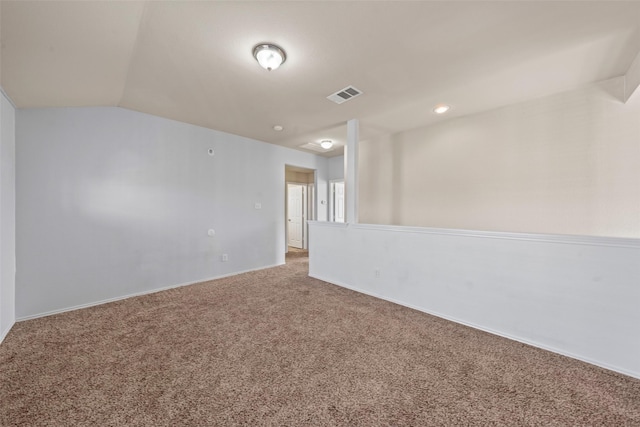 carpeted spare room with baseboards, vaulted ceiling, and visible vents