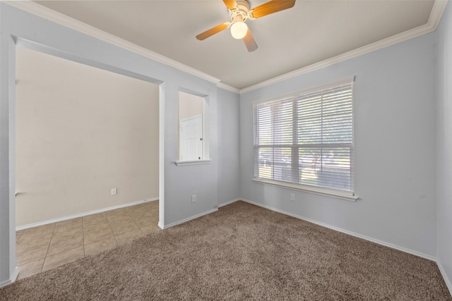 carpeted empty room featuring tile patterned flooring, baseboards, ornamental molding, and a ceiling fan