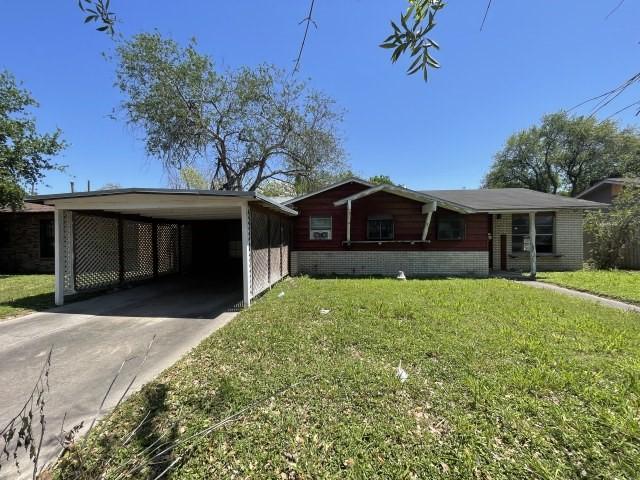 ranch-style home with brick siding, a front lawn, a carport, and driveway