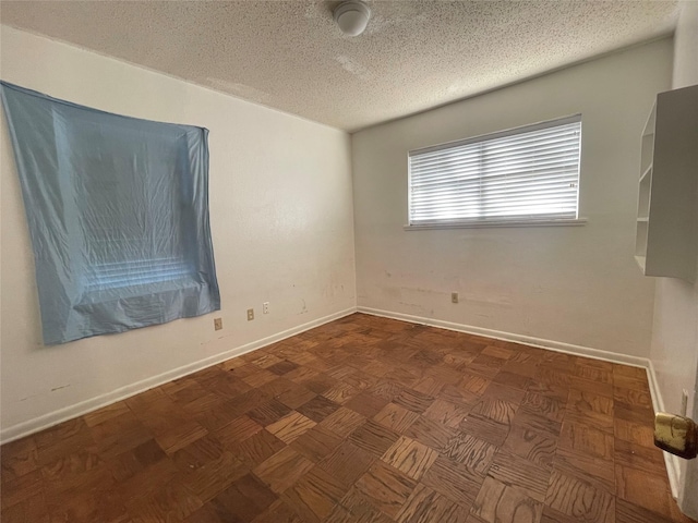 unfurnished room featuring a textured ceiling and baseboards