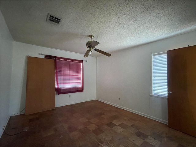 empty room featuring baseboards, visible vents, a textured ceiling, and a ceiling fan
