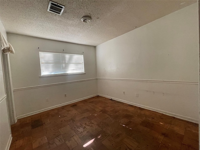 spare room with visible vents, baseboards, and a textured ceiling
