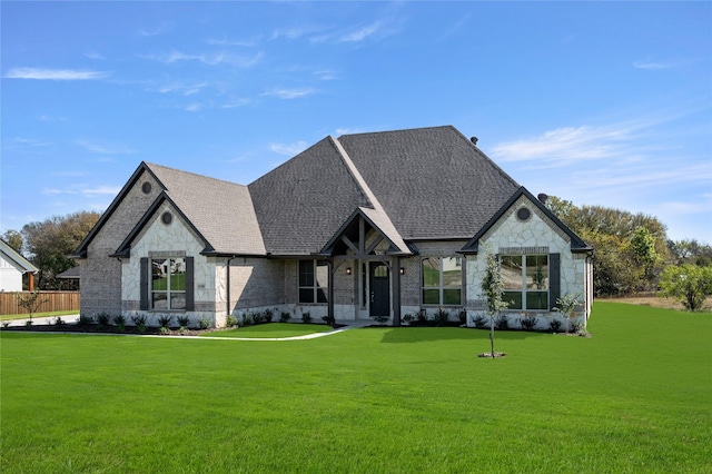 view of front of house with roof with shingles, stone siding, a front yard, brick siding, and fence