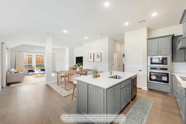 kitchen with gray cabinets, open floor plan, a sink, and stainless steel appliances