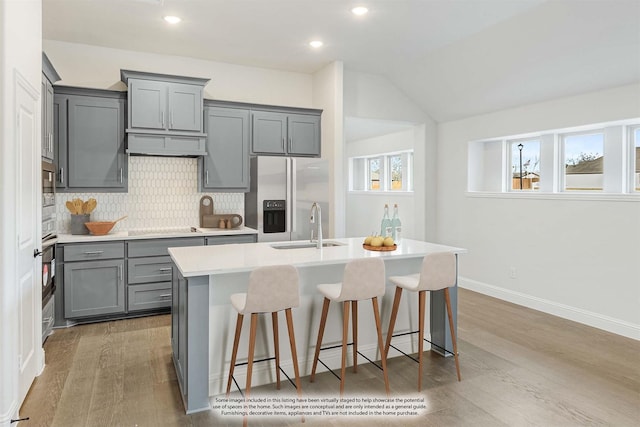 kitchen with tasteful backsplash, a sink, light countertops, appliances with stainless steel finishes, and gray cabinetry