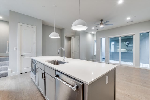 5707 Lindell Ave Unit 204, Dallas, TX 75206 - kitchen with light wood-type flooring, appliances with stainless steel finishes, a kitchen island with sink, a sink, and hanging light fixtures