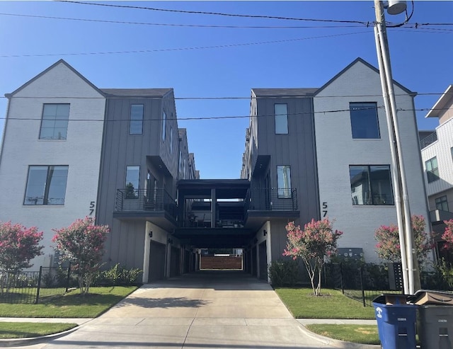 5707 Lindell Ave Unit 204, Dallas, TX 75206 - view of front facade featuring board and batten siding, concrete driveway, a front lawn, and brick siding