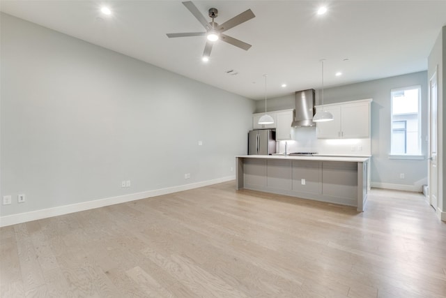 5707 Lindell Ave Unit 204, Dallas, TX 75206 - kitchen featuring light wood finished floors, freestanding refrigerator, wall chimney exhaust hood, and white cabinets