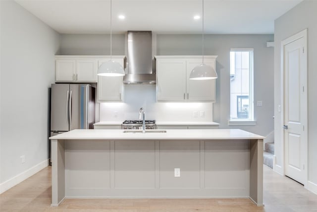 5707 Lindell Ave Unit 204, Dallas, TX 75206 - kitchen featuring an island with sink, wall chimney exhaust hood, freestanding refrigerator, white cabinetry, and light countertops