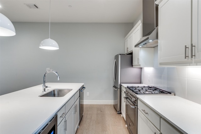 5707 Lindell Ave Unit 204, Dallas, TX 75206 - kitchen with wall chimney range hood, light countertops, stainless steel appliances, light wood finished floors, and a sink