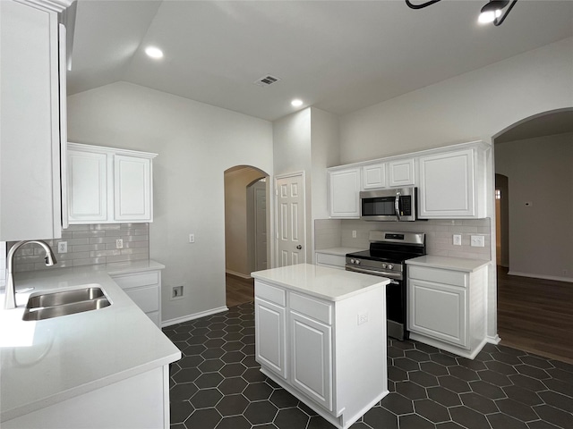 kitchen with visible vents, a center island, arched walkways, a sink, and appliances with stainless steel finishes