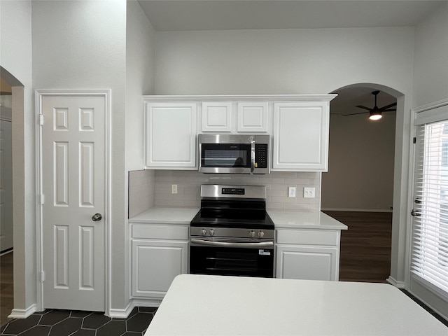 kitchen featuring arched walkways, appliances with stainless steel finishes, ceiling fan, and backsplash