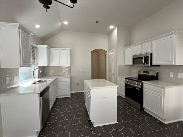 kitchen featuring arched walkways, visible vents, a kitchen island, appliances with stainless steel finishes, and a sink