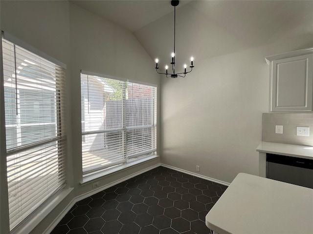 unfurnished dining area featuring dark tile patterned floors, baseboards, an inviting chandelier, and lofted ceiling
