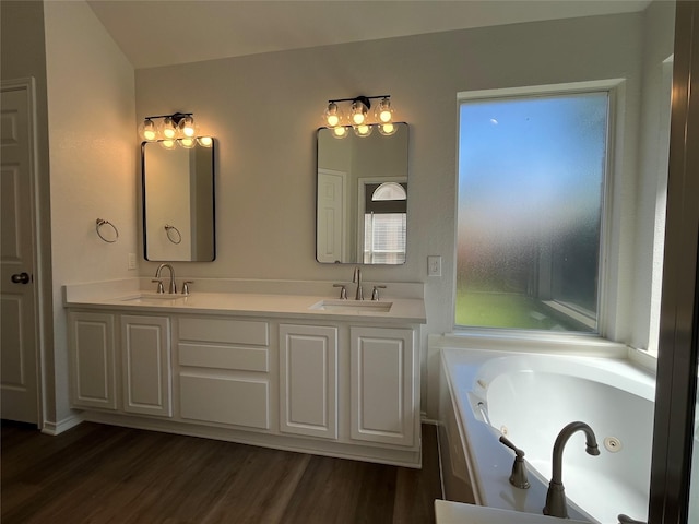 full bath with wood finished floors, a sink, and a jetted tub