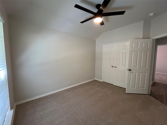 unfurnished bedroom featuring a closet, baseboards, dark carpet, ceiling fan, and vaulted ceiling