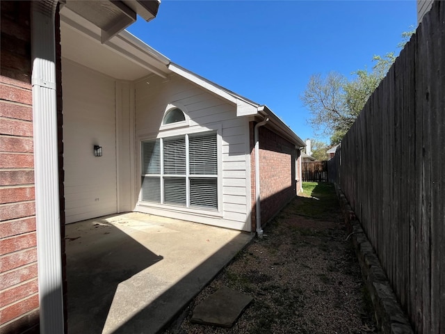 view of home's exterior with a patio area, brick siding, and a fenced backyard
