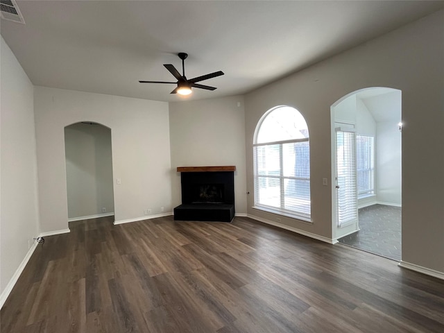 unfurnished living room with arched walkways, visible vents, dark wood finished floors, and ceiling fan