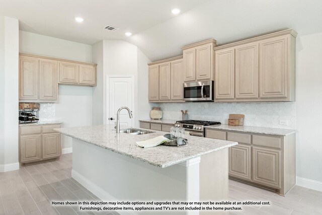 kitchen featuring light brown cabinets, backsplash, a kitchen island with sink, stainless steel appliances, and a sink