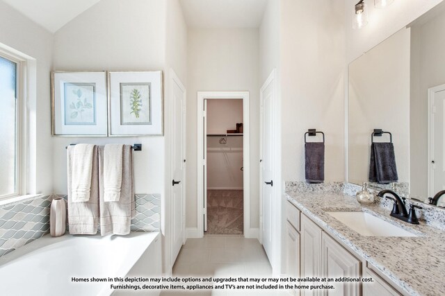 bathroom featuring vanity, a walk in closet, tile patterned flooring, and a garden tub