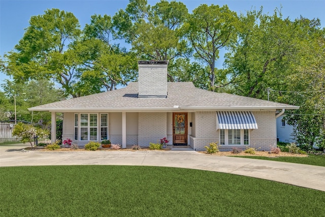 ranch-style home featuring a chimney, fence, brick siding, a front lawn, and roof with shingles