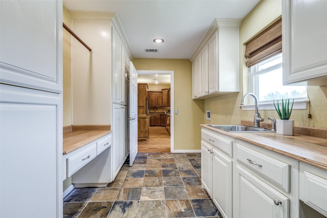 interior space with stone finish floor, light countertops, a sink, baseboards, and visible vents