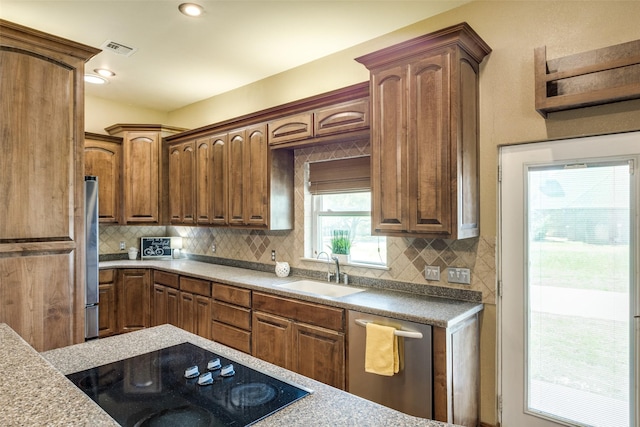 kitchen with a sink, appliances with stainless steel finishes, visible vents, light countertops, and backsplash