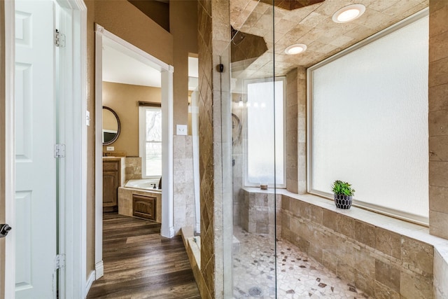 bathroom with a garden tub, vanity, a shower stall, and wood finished floors